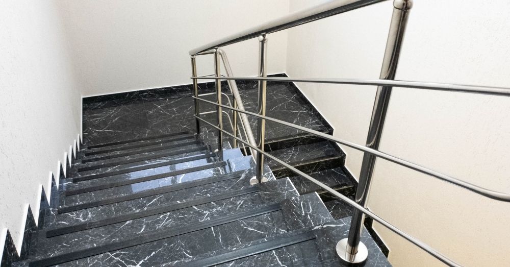A set of black marble stairs with a metal railing.
