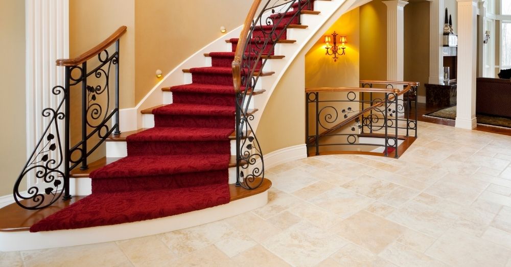 A grand staircase with a red carpet and iron railing.